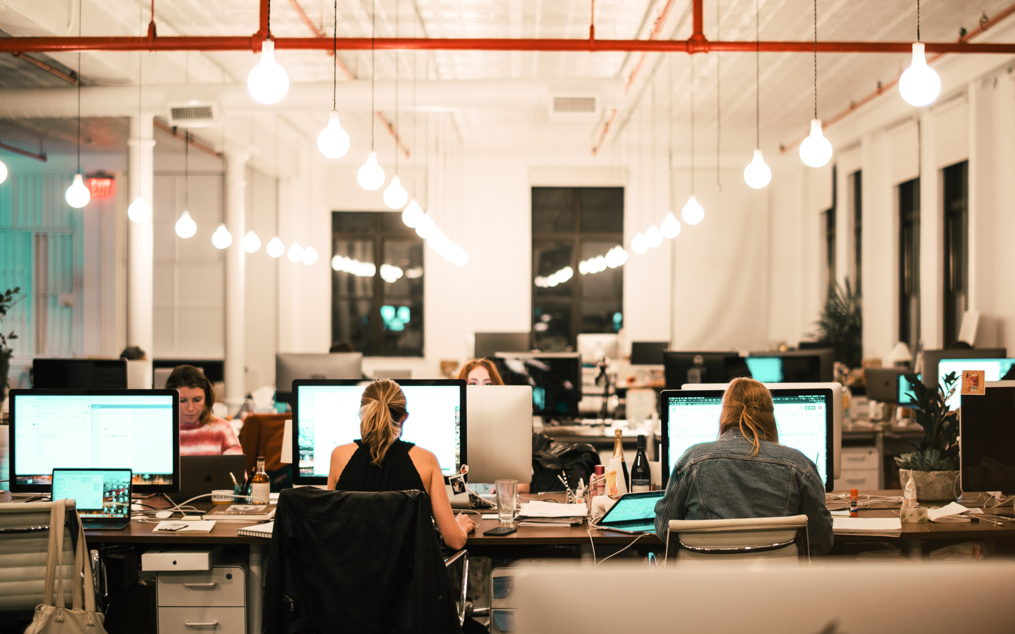 A group of people sitting in front of computers at their desks.